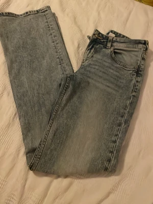 Ljusblå boot cut  jeans med tvättad look - Säljer ett par ljusblå jeans med boot cut passform och klassisk femficksdesign. Jeansen har en snygg tvättad finish och normal midja. Perfekta för en avslappnad och trendig stil. Materialet är denim i bomull.
