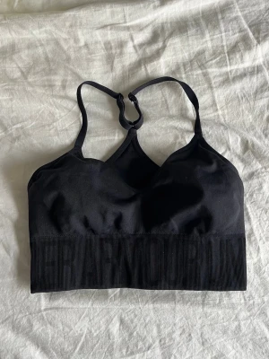 Svart sport-bh från Under Armour - Säljer en svart sport-bh från Under Armour med brottarrygg och justerbara axelband. Bh:n har en bred resår under bysten och är tillverkad i ett stretchigt funktionsmaterial som passar perfekt till träning. Diskret logga framtill.