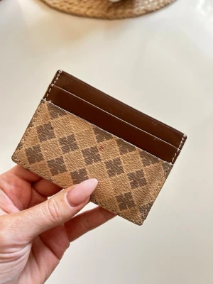 Brun rutmönstrad kortfodral - Så snyggt kortfodral i brunt och beige med klassiskt rutmönster från Malene Birger, lite skavt på ena sidan + fläck på framsidan som borde gå bort 