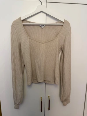 Beige ribbad topp från Bubbleroom - Säljer en beige ribbad långärmad topp från Bubbleroom. Toppen har en v-ringad urringning och är croppad i modellen. Perfekt att matcha med både jeans och kjol för en trendig look.