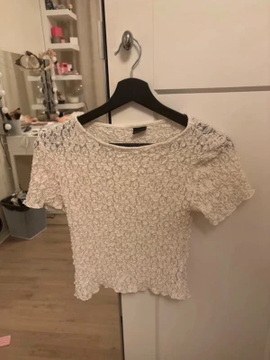 Vit spetsblus från Gina Tricot - Pris går att diskutera. Supersöt vit spetsblus från Gina Tricot i storlek S. Blusen har korta ärmar, rund halsringning och är tillverkad i ett stretchigt spetsmaterial med blommigt mönster. Perfekt att styla med jeans eller kjol för en trendig look.