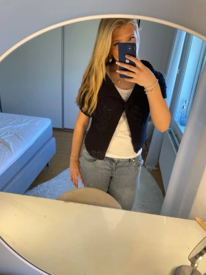 Svart stickad Bolero - Snygg svart stickad kofta med korta ärmar och bred krage. Koftan har ett öppet framstycke och ett fint hålmönster på axlarna. Perfekt att slänga över en t-shirt för en trendig lager-på-lager-look. Använt fåtal gånger , vet ej vilken strl men passar mig som har s/ m 