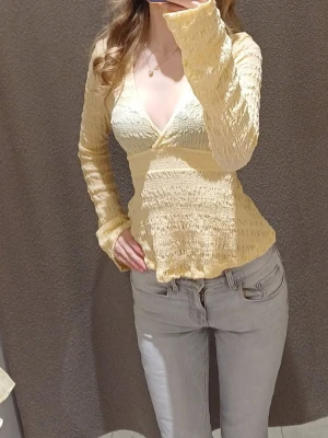 Gul omlottopp med volangärm -  SÖKER! gul omlottopp med lång ärm och volangdetaljer vid ärmslut och nederkant. Toppen är v-ringning 