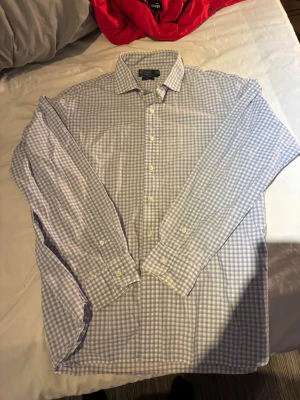 Rutig skjorta från Polo Ralph Lauren - Klassisk långärmad skjorta från Polo Ralph Lauren i ljusblått och vitt rutigt mönster. Skjortan har knappar framtill och på ärmsluten samt en snygg krage. Tillverkad i mjuk bomull som känns skön mot huden.