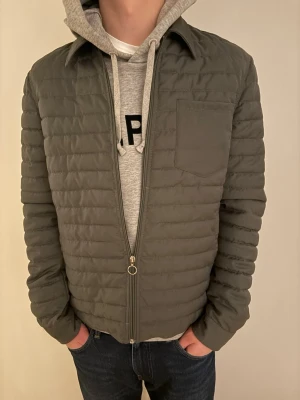 Mörkgrön Samsøe Samsøe quiltad pufferjacka - PRIS KAN DISKUTERAS‼️Säljer en mörkgrön Samsøe Samsøe pufferjacka med quiltad design och långärmad passform. Jackan har en bröstficka, klassisk krage och dragkedja framtill. Perfekt för kalla dagar och snygg att matcha med hoodie eller t-shirt.