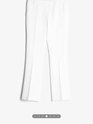 Vita utsvängda kostymbyxor - Säljer ett par jättefina vita kostymbyxor. Byxorna har låg midja, fickor i sidorna. Perfekta för en clean och stilren look. Materialet ser ut att vara en mjuk och följsam blandning, troligtvis polyester eller bomull. Endast använt dem 1 gång💕