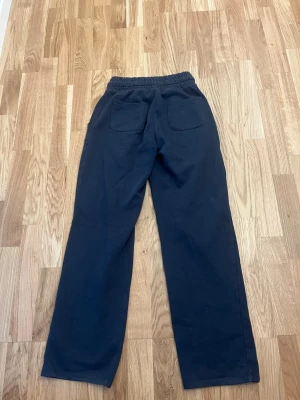 Mörkblå mjukisbyxor från 157 - Mörkblå mjukisbyxor från lager 157 med raka ben och resår i midjan. Byxorna har två bakfickor och är gjorda i mjukt, fleeceliknande material som är perfekt för chill dagar. Enkel och clean design som passar till det mesta.