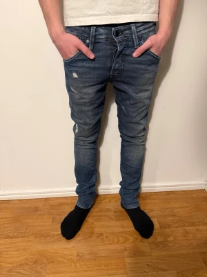 Blå slitna slim jeans från jack&jones  - Säljer ett par blå slimfit jeans från jack&jones med slitningar och distressed detaljer på låret och knät. Jeansen har klassisk femficksmodell, låg midja och nice passform. Jeansen är i storlek w29 l32 Perfekta för en avslappnad och trendig look. Pris kan diskuteras ✅