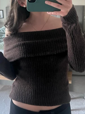 Brun off shoulder stickad tröja H&M - Mysig brun ribbstickad off shoulder-tröja från H&M. Tröjan har långa ärmar och bred krage som kan bäras nedanför axlarna. Perfekt för dig som gillar en avslappnad men ändå stilren stil.