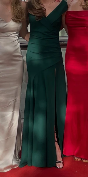 Grön balklänning  - Elegant mörkgrön långklänning med omlott-design. Klänningen har en slits framtill och är ärmlös, perfekt på balen, bröllopet eller festen. Använd endast en gång, ny skick! Pris diskuterbart vid snabb affär. 