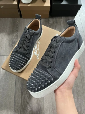 Gråa Christian Louboutin sneakers - Snygga gråa sneakers från Christian Louboutin i mocka med coola nitar på tån🙌🏻 Storlek 41 i fint skick😇 Hör av er vid minsta fundering. Pris ej hugget i sten🤩