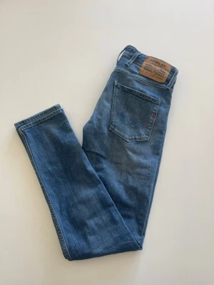 Blå raka jeans från Replay - Snygga blå jeans från Replay med klassisk femficksdesign och raka ben. Jeansen har en läderpatch med Replay-logga bak i midjan och är gjorda i mjukt denimtyg. Perfekta för en avslappnad och trendig look. Hör av er med frågor!!!