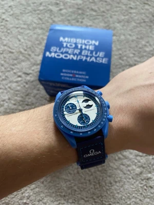 Omega x Swatch blå Moonphase klocka - Säljer en Omega x Swatch Mission to the Super Blue Moonphase klocka. Klockan har blå boett och armband med vit urtavla och blå detaljer. Moonphase-funktion och biokeramisk konstruktion. Kommer i originalförpackning.
