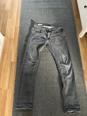 Grå slim fit jeans från Replay - Snygga grå slim fit jeans från Replay med klassisk femficksmodell och slitna detaljer. Jeansen har en något tvättad look och är tillverkade i mjukt denimtyg med stretch för extra komfort. Perfekta för en avslappnad och trendig stil.