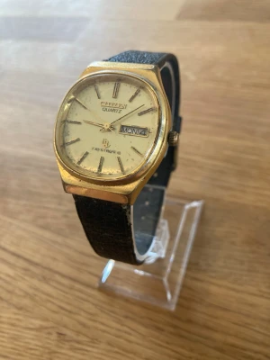 1980 Citizen Crystron Day Date Gold 32mm Herrur - Säljer en ovanlig vintage Citizen Crystron klocka med dag- och datumfunktion som är Citizens svar på Seiko Astron. Boetten är guldpläterad och baksidan är i rostfritt stål. Klockan har ett svart läderarmband. Urverket är kvartsbatteri och behöver bytas. Skicket är fint enligt bilder och det du ser är mestadels smuts snarare än skador. Case nr: 4-853491 TA. Andra koder: 8110312, 42-6122, GN-5-0.  Begagnat värde: < 3000 SEK Mitt pris: 989 SEK  Skickas alltid snabbt och spårbart. Skriv vid frågor.