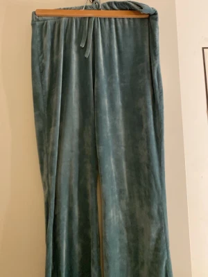 Gröna velour mjukisbyxor - Mysiga gröna mjukisbyxor i mjuk velour med rak passform och resår i midjan. Perfekta för chill dagar hemma eller när du vill vara extra bekväm.
