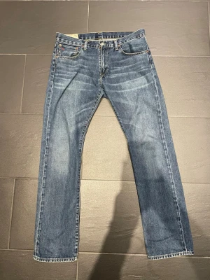 Vintadge Ralph lauren raka jeans - Klassiska blå jeans från Ralph lauren med rak passform och fem fickor. Jeansen har en snygg tvätt med subtila slitningar och kontrastsömmar. Tillverkade i slitstark denim med läderpatch bak i midjan. Perfekta för en avslappnad och tidlös stil.