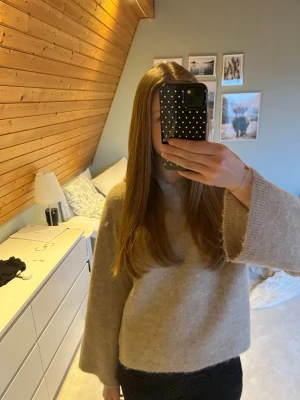 Beige hoodie med vida ärmar - Mysig beige hoodie med breda, vida ärmar och lös passform. Tillverkad i ett mjukt, stickat material. Perfekt för dig som gillar en avslappnad och trendig stil. Huvan är stor och ger en chill vibe.