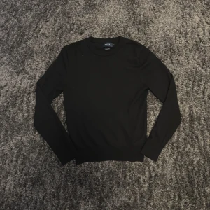 Svart merinoullströja från Riley - Säljer en klassisk svart tröja från Riley i mjuk merinoull. Tröjan har rund halsringning och långa ärmar, perfekt för lager-på-lager eller som den är. Enkel och stilren design som passar till mycket.