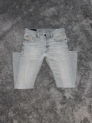 Ljusgrå slim fit jeans från Diesel - Säljer ett par ljusgrå slim fit jeans från Diesel med klassisk femficksdesign. Jeansen har slim-fit passform och är tillverkade i mjuk denim med stretch för extra komfort. Perfekta för en avslappnad och trendig look.