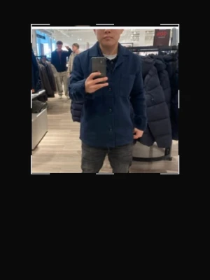 Mörkblå overshirt med knappar - Stilren mörkblå overshirt med klassisk krage och knäppning framtill. Modellen har raka ärmar och två sidofickor. Perfekt att bära över en t-shirt för en avslappnad look. Materialet ser ut att vara bomull eller en bomullsblandning.