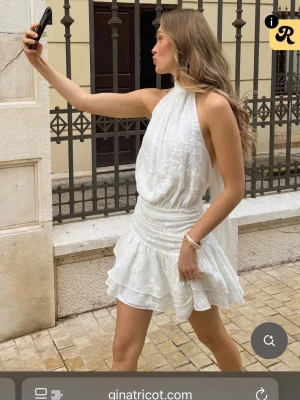 Studentklänning - Säljer en vit kort klänning från Gina Tricot med halterneck och öppen rygg. Perfekt till studenten, midsommar eller andra somriga tillställningar. Helt ny då jag beställde 2 stolekar🌟
