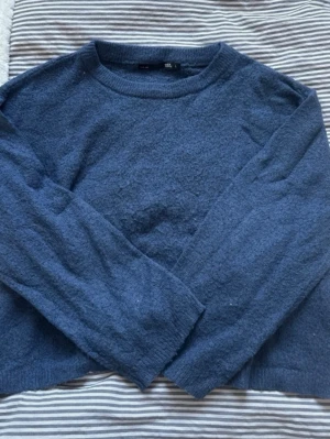 Mörkblå stickad tröja - Mysig mörkblå stickad tröja med rund halsringning och långa ärmar. Tröjan har en enkel, klassisk design och är tillverkad i ett mjukt, fluffigt material som känns skönt mot huden. Perfekt för kyliga dagar och enkel att matcha med olika outfits.