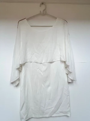 Vit klänning  - Vit klänning perfekt inför student, med en volang upptill som sträcker sig över armarna🌸 - Brons/guldig gitter rand från axlarna och längst med ärmarna - 95% polyester, 5% elastan - Okänt märke - One size