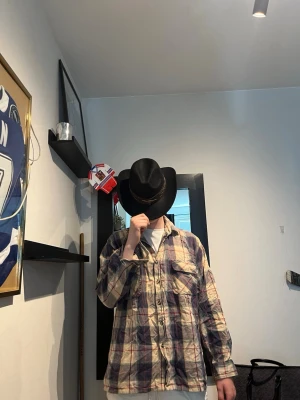 Rutig oversized skjorta i bomull - Säljer en oversized rutig skjorta i bomull med beige, blå och röda toner. Skjortan har klassisk krage, knappar framtill och långa ärmar. Perfekt för en avslappnad och trendig look. Modellen är 182 och väger 75 kg den ska va som en overshirt 