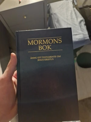 Mormons bok - Ännu ett testamente - Mörkblå inbunden bok med guldfärgad text på omslaget. Titeln är 'Mormons bok: Ännu ett testamente om Jesus Kristus'. Perfekt för dig som är intresserad av religiös litteratur och vill utforska mormonismens heliga skrifter.
