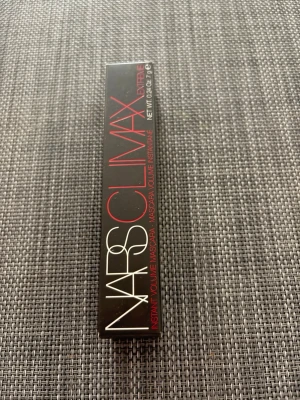 NARS Climax Extreme Mascara svart - NARS Climax Extreme Mascara i svart ger intensiv volym till fransarna. Snygg, matt svart tub med räfflad design och vit logga. Förpackningen är svart med röda och vita detaljer. Perfekt för dig som vill ha dramatiska fransar och en lyxig känsla i sminkväskan.