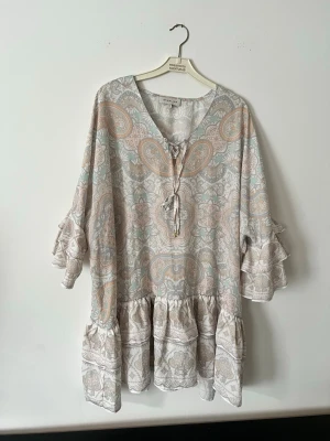 Klänning  - Superfin klänning med paisleymönster och volangdetaljer från By Malina. Perfekt för sommarens alla tillfällen