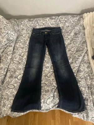 Mörkblå bootcut jeans - Säljer ett par mörkblå bootcut jeans med lätt slitningar framtill. Jeansen har en snygg utsvängd passform och kontrastsömmar.Perfekta för dig som vill ha ett par jeans som sticker ut lite!