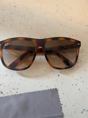 Bruna solglasögon från Ray-Ban - Snygga solglasögon från Ray-Ban med klassisk brunsköldpaddsmönstrad båge och bruna tonade glas. Modellen har en tidlös och trendig form som passar till många stilar. Tillverkade i Italien och perfekta för soliga dagar.