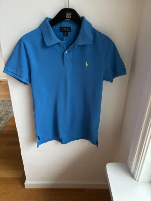 Blå pikétröja från Polo Ralph Lauren - Snygg Ljusblå Ralph Lauren piké i st L 14-16 år för endast 175kr. Nypris 750kr 