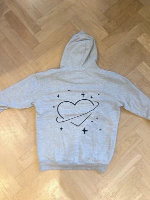 Grå hoodie med hjärta och stjärnor från Mira Paris - Ljusgrå hoodie från Mira Paris i storlek S med tryck på ryggen. Superfin men kommer tyvärr inte till andvändning🤍