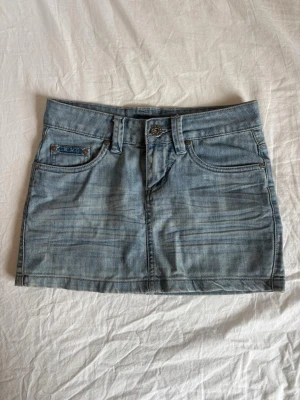Ljusblå kort jeanskjol  - Jätte snygg jeanskjol med snygga fickor. Midjemått : ca 36 cm. Längd: ca 30 cm. 
