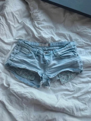 Lågmidjade jeansshorts - Ljusblåa jeansshorts från fishbone med låg midja i storlek s, alla mått finns på sista bilden