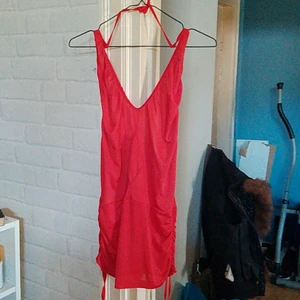 Röd halterneck - Kort kort halterneck klänning med djup ringning man kan ställa längden själv och öppen rygg till svanken samt dragsko man kan ställa passform/längd. Använd en gång 