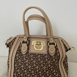 Brun DKNY väska  - Säljer för att den inte passar min stil. Bra skick  Bredd: 26 cm  Höjd: 26cm  Djup: 17cm 