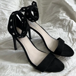Svarta klackar med ankeldetajl  - Jätte fina klackar i mocka imitation. Snygga detaljer på bandet runt ankeln. Endast testade.                                                             Klackhöjd: 10,5 cm.                                                                          Nypris: 499:-