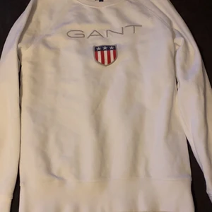 Vit Gant shield logo c-neck - Vit gant tröja! Nypris: 599kr. Använd men funkar fortfarande bra och är inte sönder någonstans. Storlek: M men passar dig som är S då den är lite för liten för mig som är 185. Plagget är garanterat ditt efter Swish!