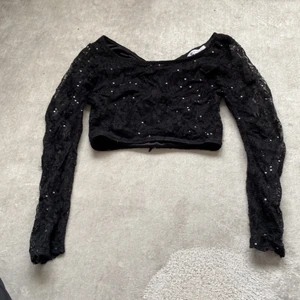 En croctop  - Det är en svart croctop med gliter men det ramlar inte av den är spets och har kedja 