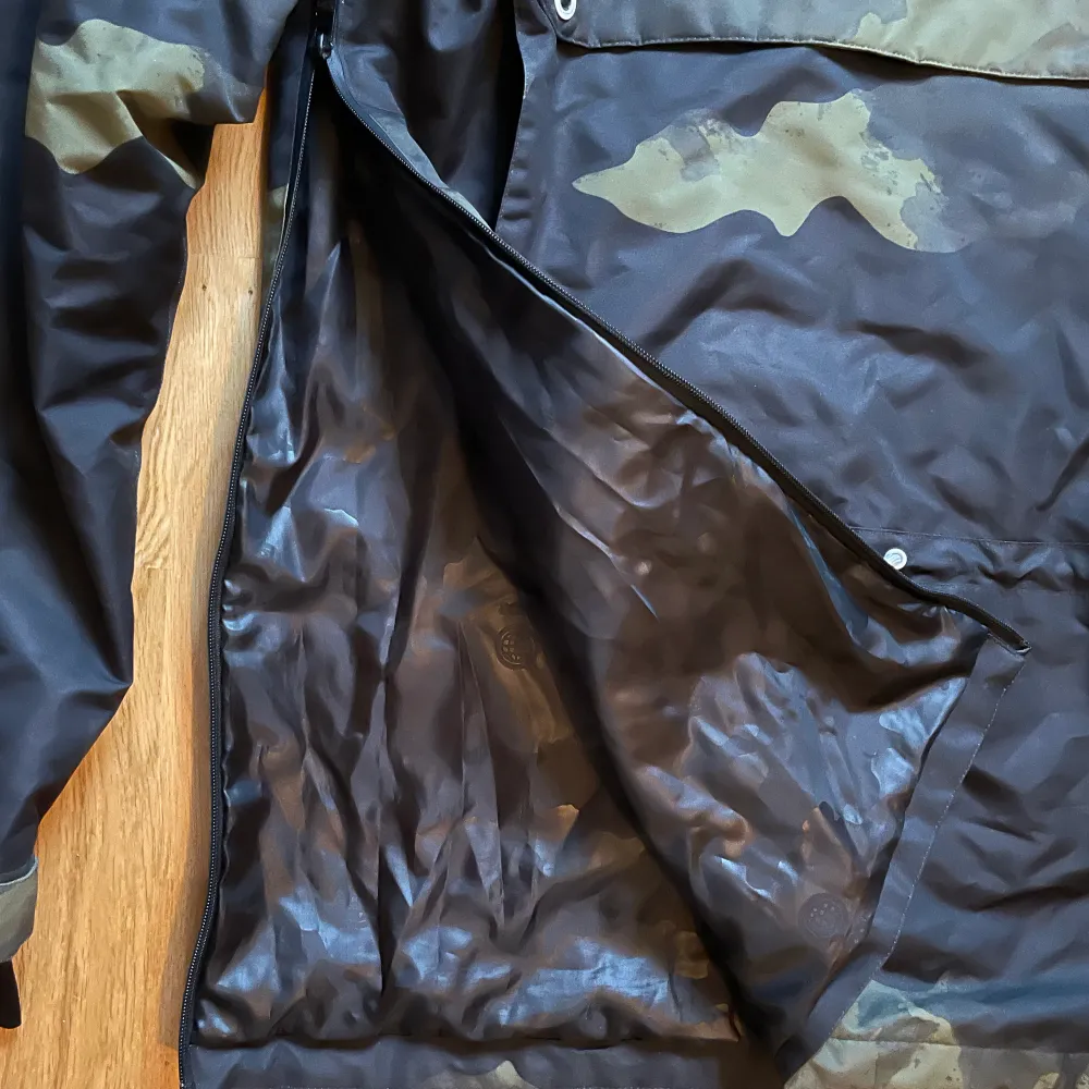 Anorak skidjacka från märke Dope. Militärmönster. Två st fickor på magen. En ficka för liftkort på ena ärmen. Dragkedjor på sidorna för ventilation. Luva som går att få över skidhjälm. Använd 1 vecka i fjällen. Inget tecken på slitage. . Takit.