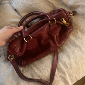 Röd sandro väska - Superfin röd väska ifrån sandro. Perfekt till våren. I använt skick för har lite slitningar men fortfarande i bra skick. 300kr + 69kr frakt