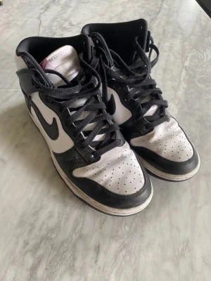 Nike Dunk SB High Pandas - Skick 8/10 endast använda några gånger, köptes för 2,500 men säljes för 1,200. Har storlek 44 men sitter som en 42. Kommer med låda samt extra snören