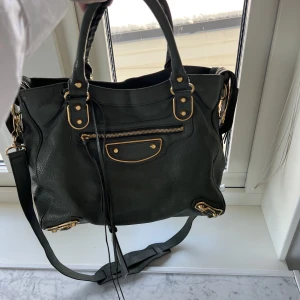 Balenciaga Väska - Säljer nu min Balenciaga city- velo väska. I grön/ grå med guld detaljer. Inget kvitto eller äkthesbevis finns, men man kan se på bla deagkjedjan och serienummret att den är äkta. Skriv för fler bilder eller frågor❤️
