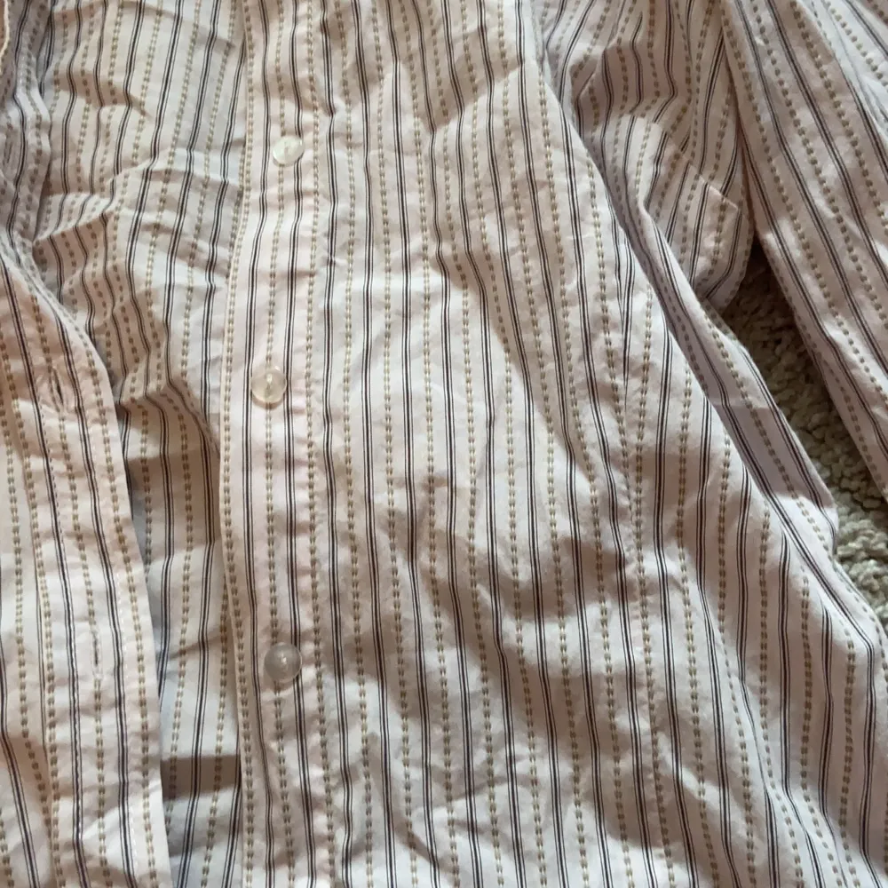 Fin ljusrosa skjorta med grå ränder! Bra skick, dock är lappen lite trasig men inget som syns. Skjortor.