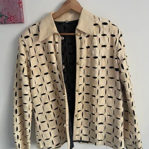 Vit/beige skinnjacka med coolt mönster - En tunnjacka i coolt mönster i en vit/beige färg. Använd fåtal gånger men är något sliten då den är köpt secondhand. Storleken är XXL men den sitter oversized på mig som normaltvis har S.