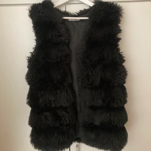 Svart pälsväst storlek M/L - Svart väst i fuskpäls i storlek M/L, men stor i storleken.
